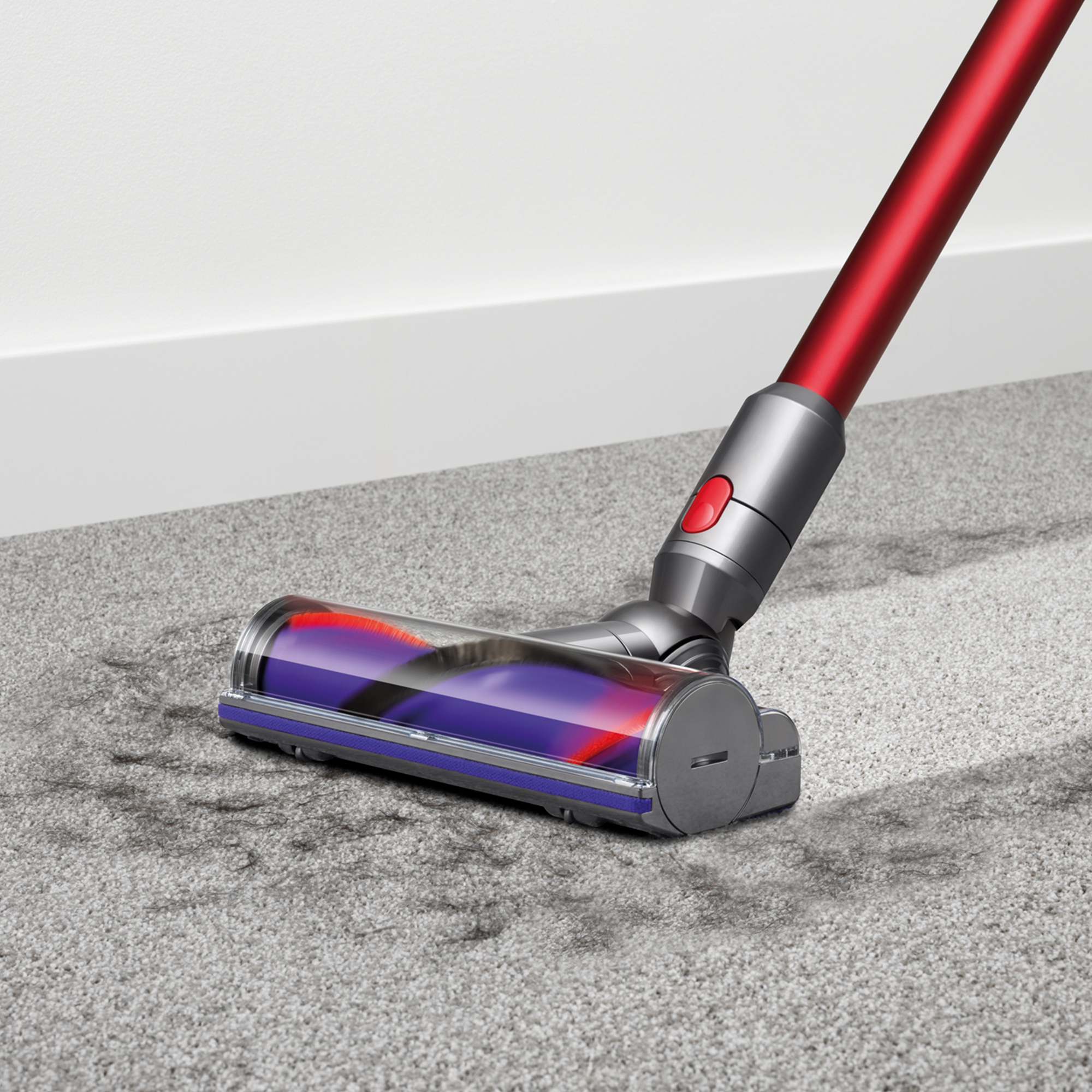 Dyson-Vakuumkopf auf Teppich, rot und grau. Saugwirkung sichtbar. Teppich ist grau.