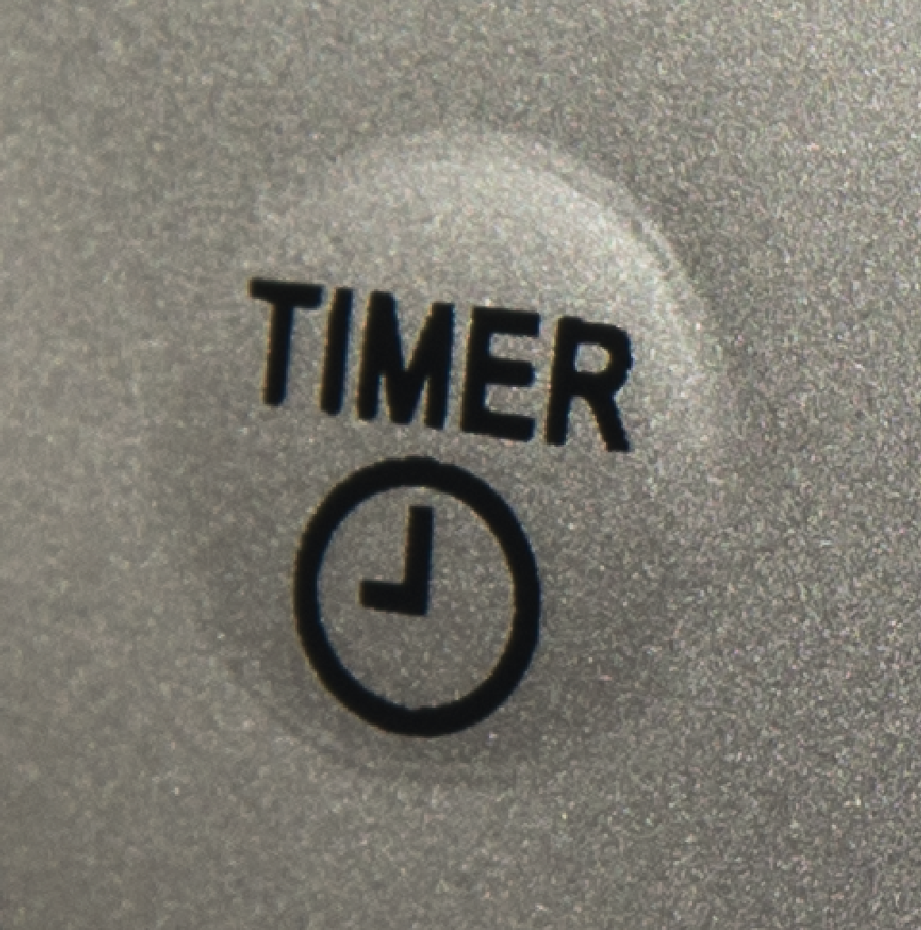 Grijze knop met 'TIMER' label en een kloksymbool, close-up.