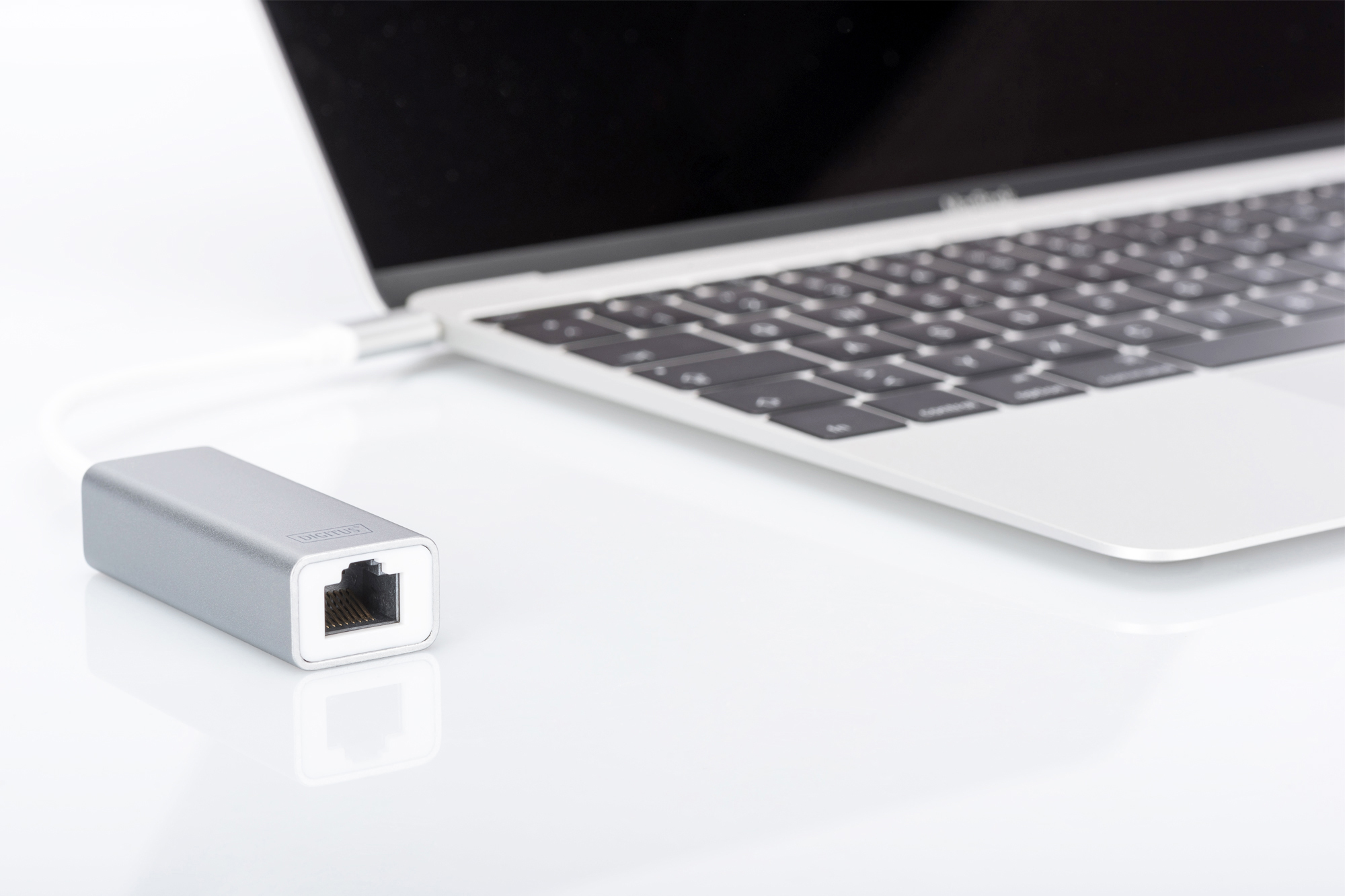 Silberner USB-C-Adapter neben einem Laptop.