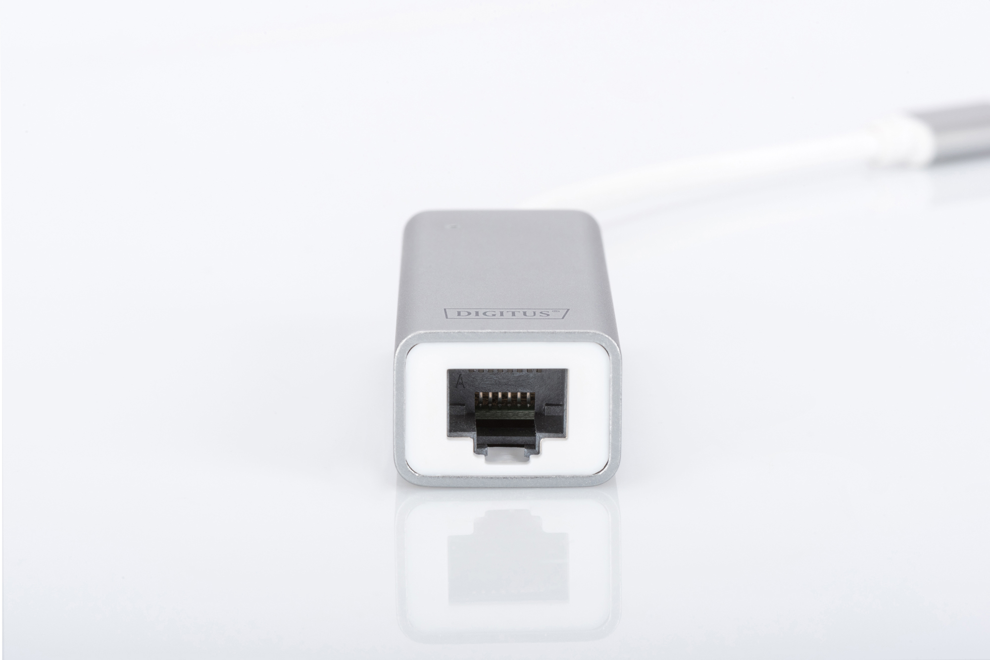 Ein silberner Digitus Ethernet-Adapter mit RJ45-Anschluss, weißem Kabel auf weißer Oberfläche. Der Anschluss ist schwarz.