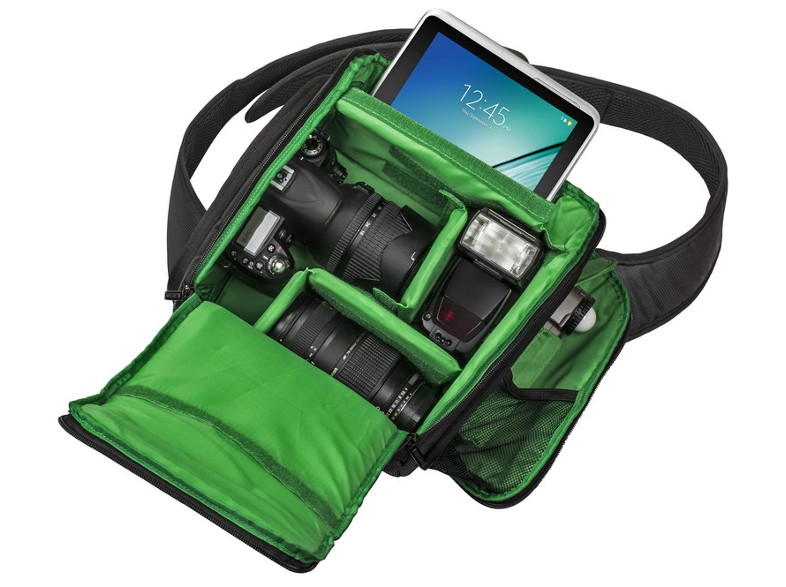 Egy nyitott kameratáska, benne DSLR, objektív, vaku és egy tablet. A belső tér zöld. A táskának vállpántja van.