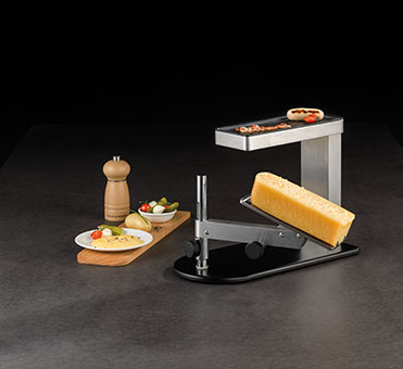 Raclette-Grill mit Käse und Essen auf einem Tisch.