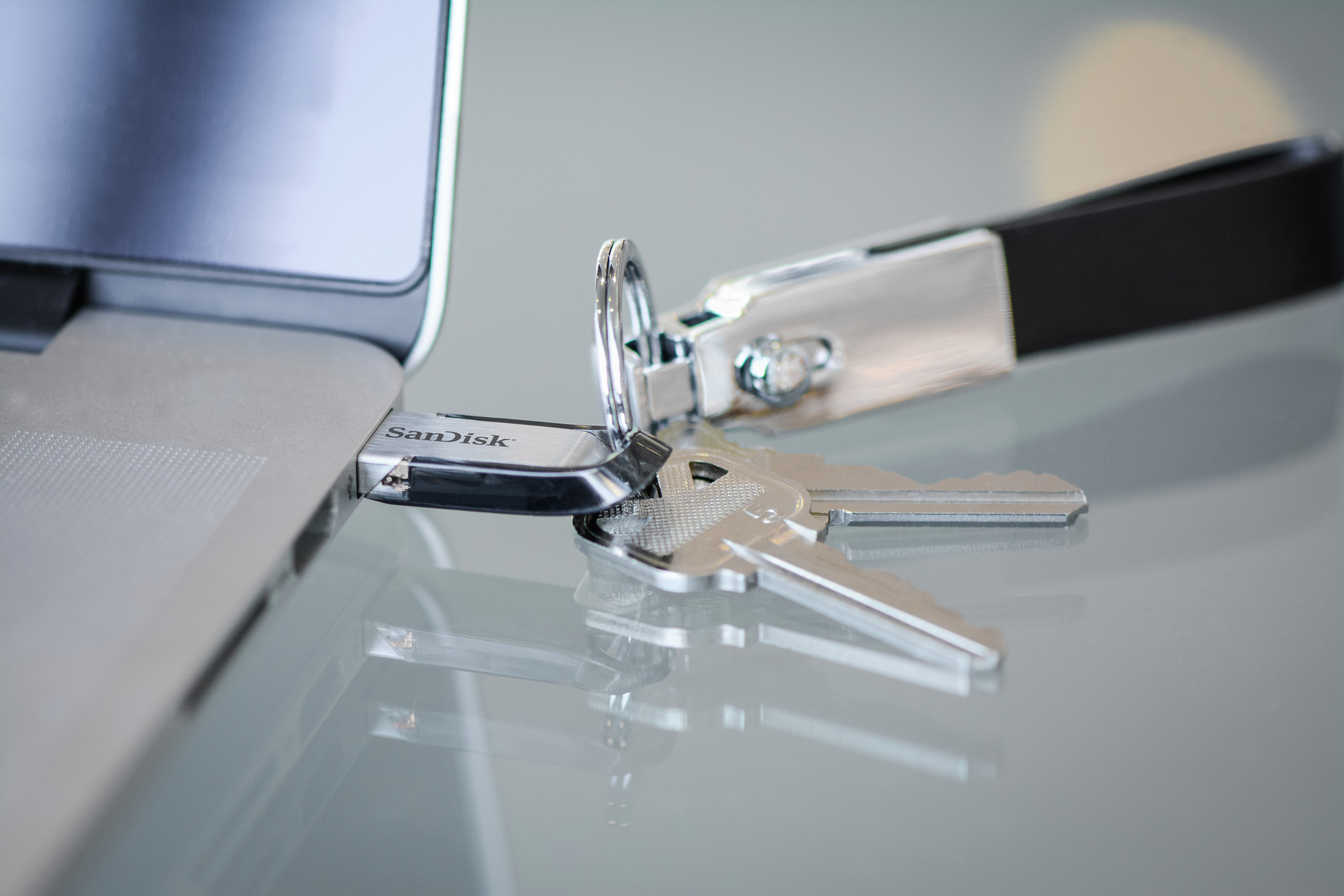 A USB drive in a laptop. There are keys on a keychain next to it.