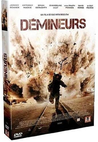 Pochette de DVD de film : Scène d'explosion. Une personne en équipement de protection court.