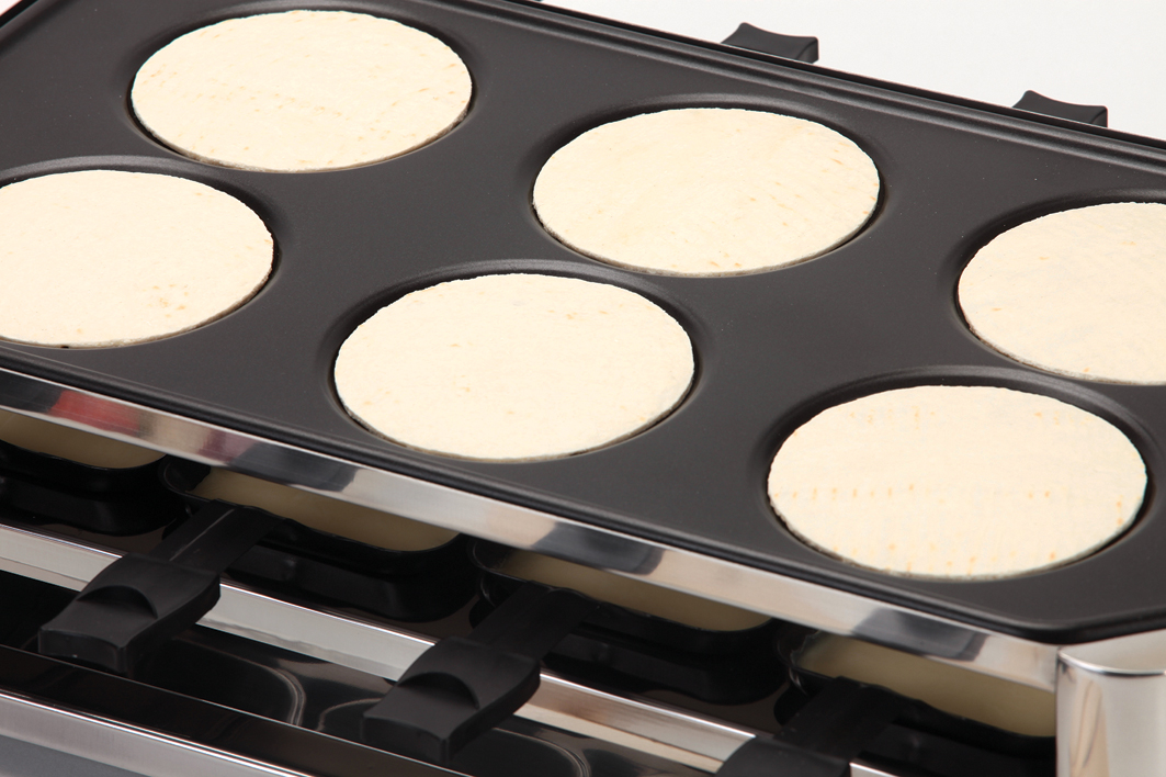 Una piastra con sei pancake circolari in cottura.