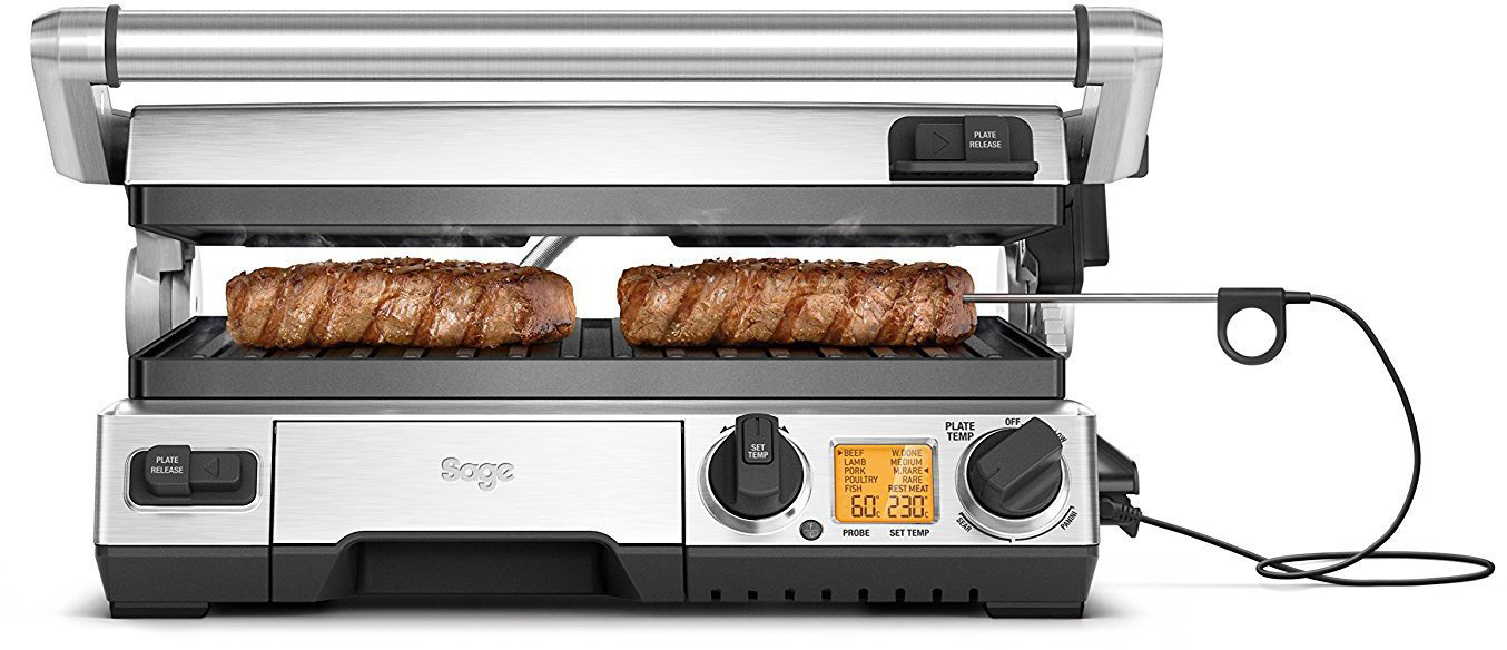 Ein silberner und schwarzer Sage-Grill mit zwei Steaks, die auf dem Grill braten.