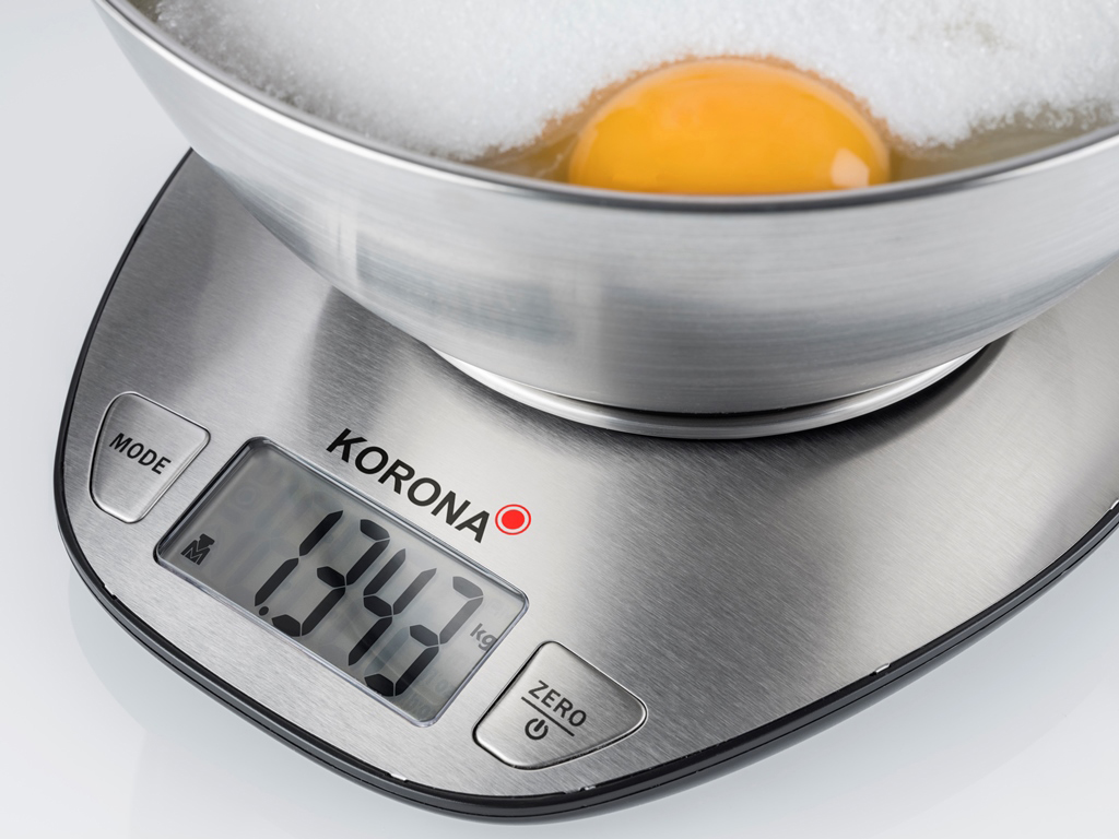Eine Digitalwaage mit einer Schüssel, die ein Ei und Zucker enthält. Die Waage zeigt 1343 g an.