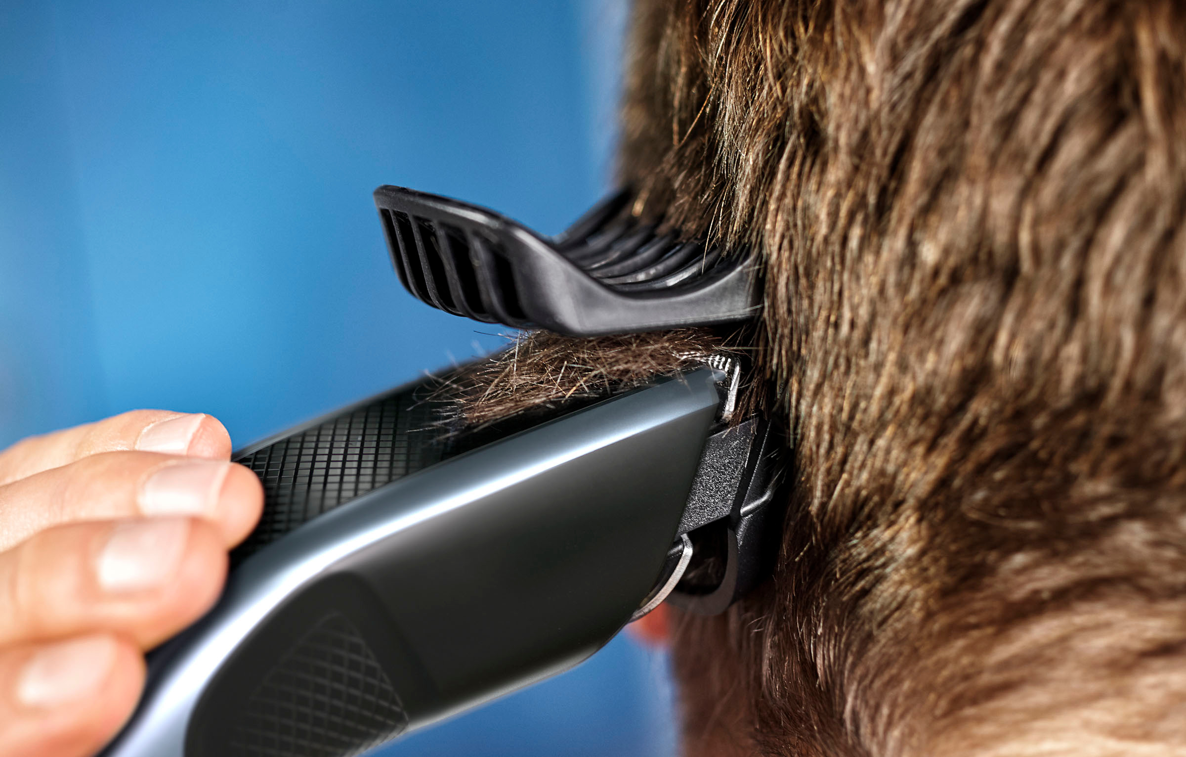 Mannes Haar wird mit einem Haarschneider geschnitten. Nahaufnahme.