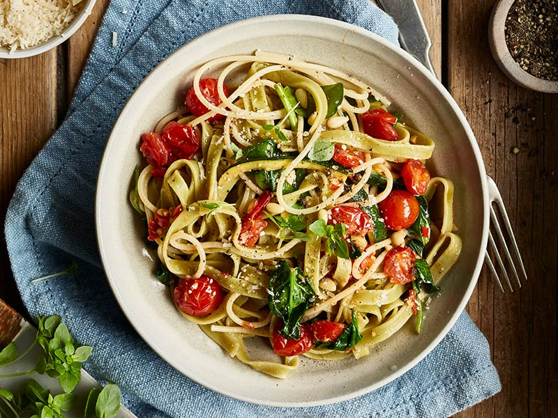 Schüssel Pasta mit Tomaten, Basilikum und Pinienkernen.