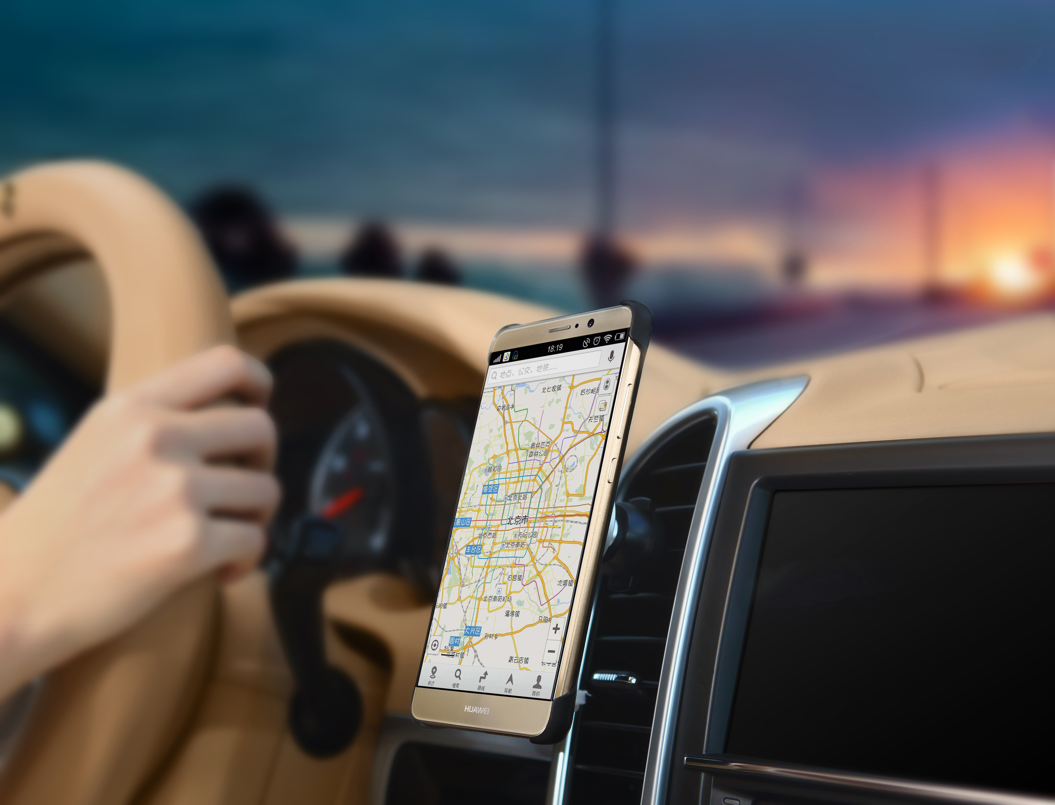 Ein Telefon auf einer Autohalterung, das eine Karte anzeigt, und die Hand einer Person am Lenkrad.