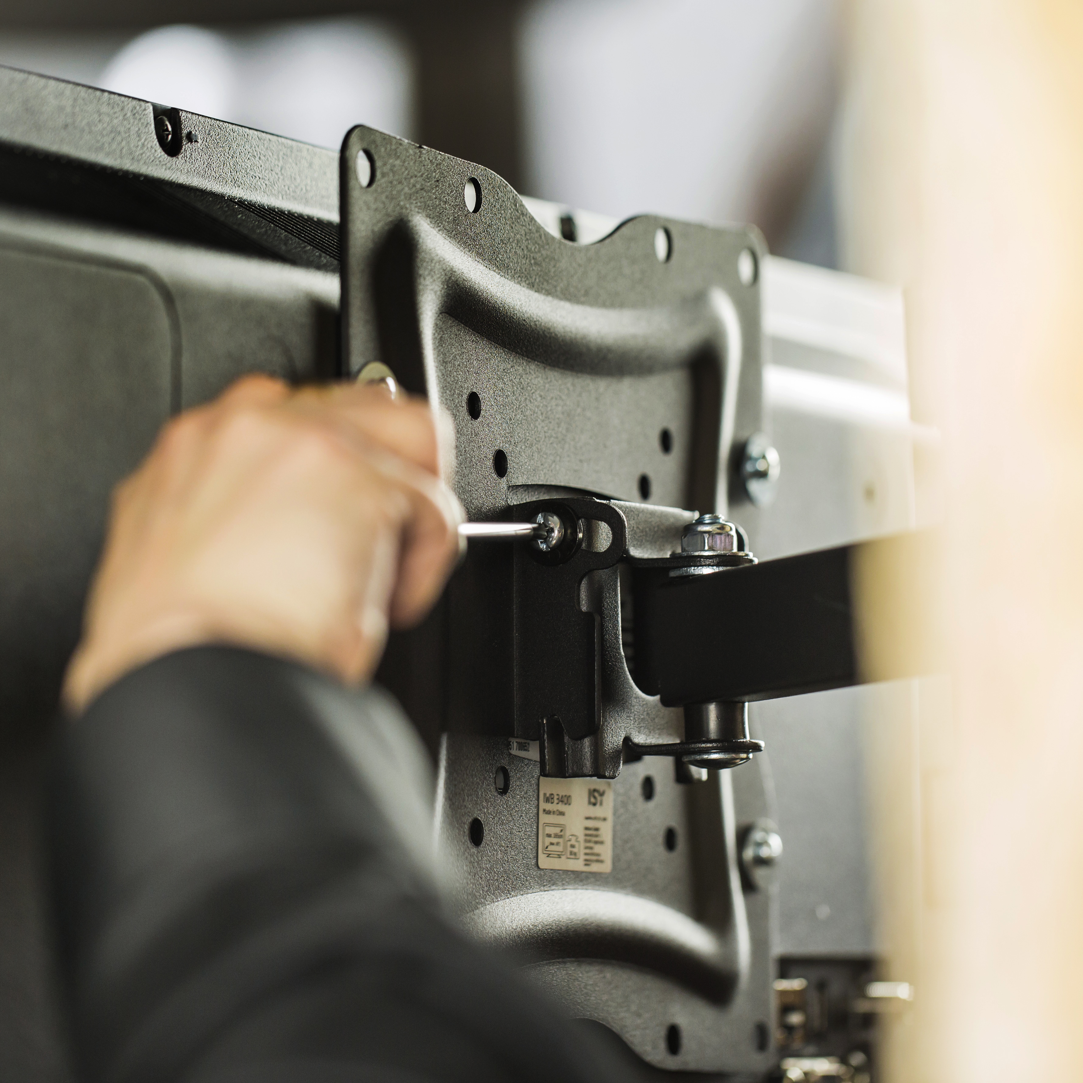 Una persona che usa un cacciavite per fissare una staffa al retro di una TV.