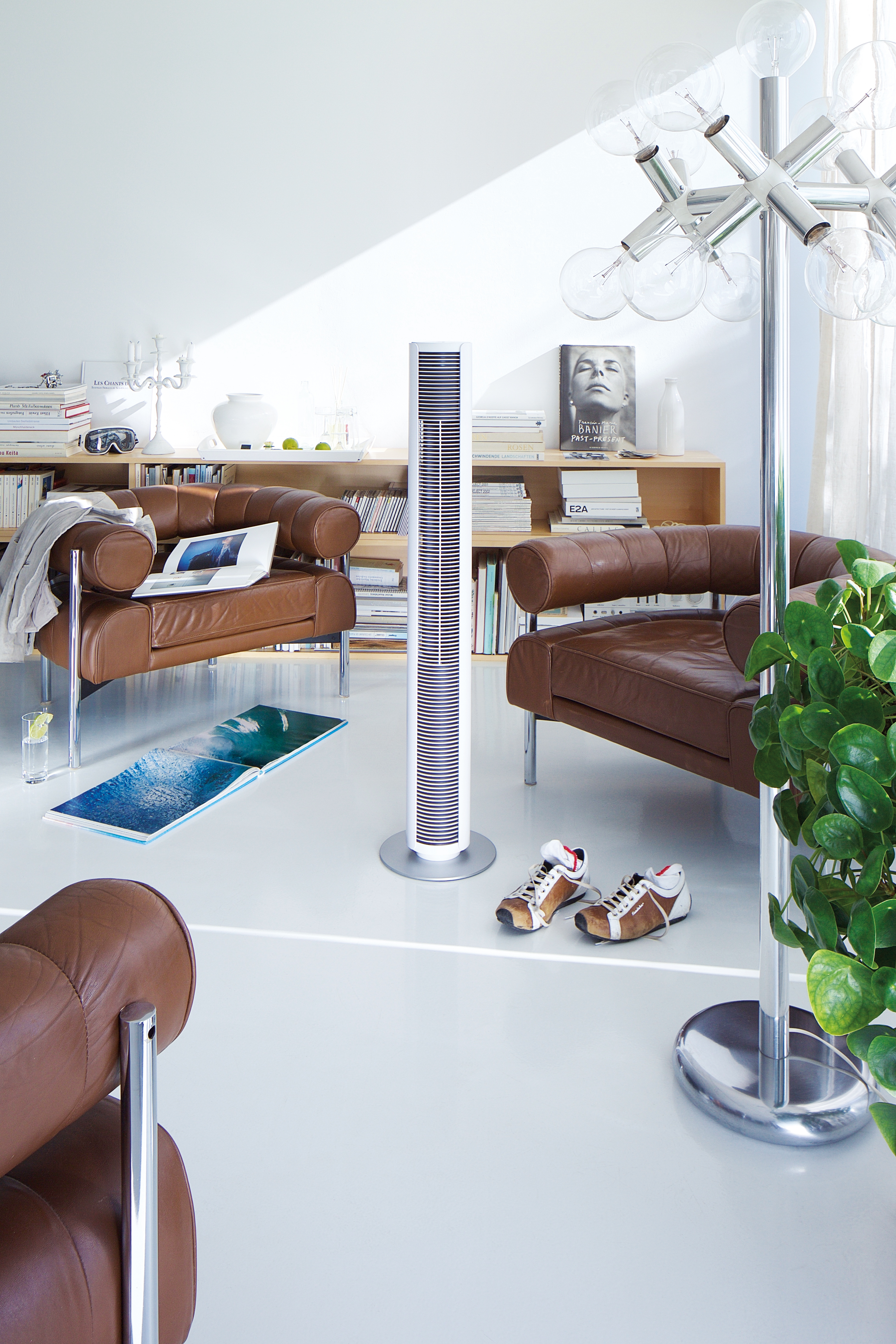 Modernes Wohnzimmer: braune Ledersessel, Ventilator und Stehlampe. Weißes Interieur.