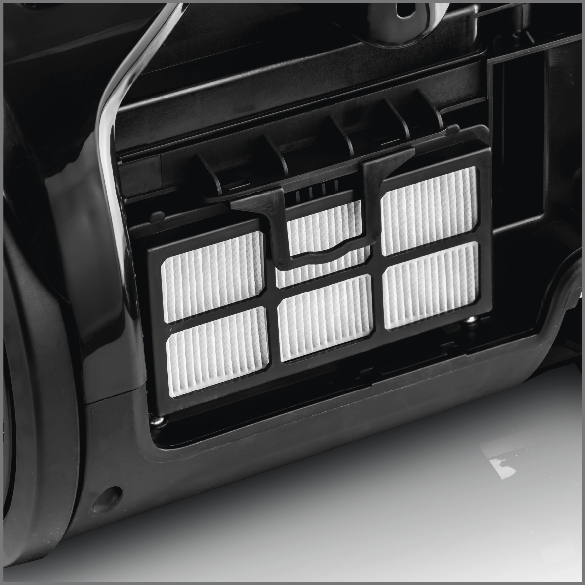 Nahaufnahme eines Staubsaugerfilterfachs. Der Filter ist rechteckig mit weißem, plissiertem Material.