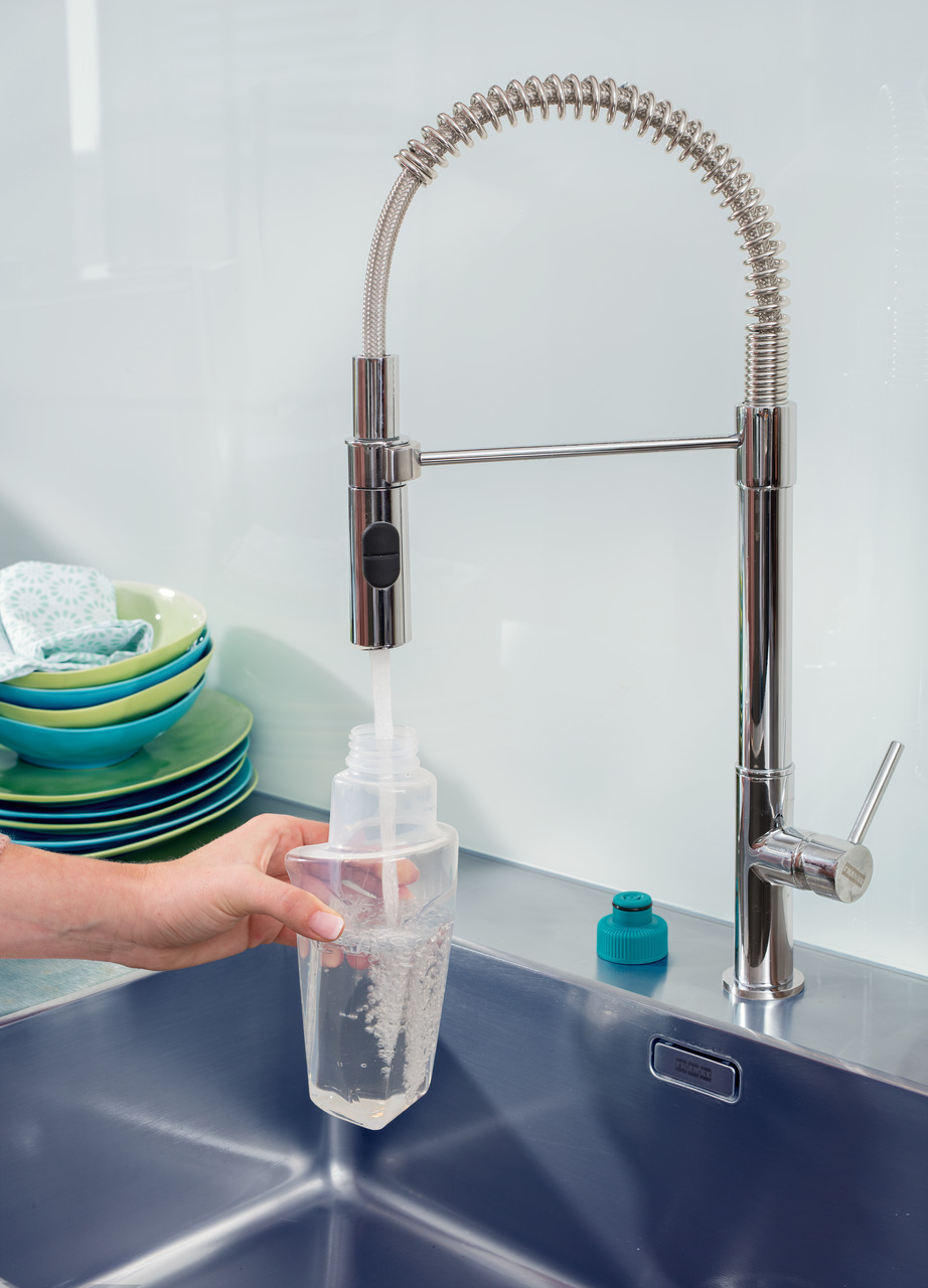 Eine Hand füllt eine Flasche mit Wasser aus einer Küchenarmatur.