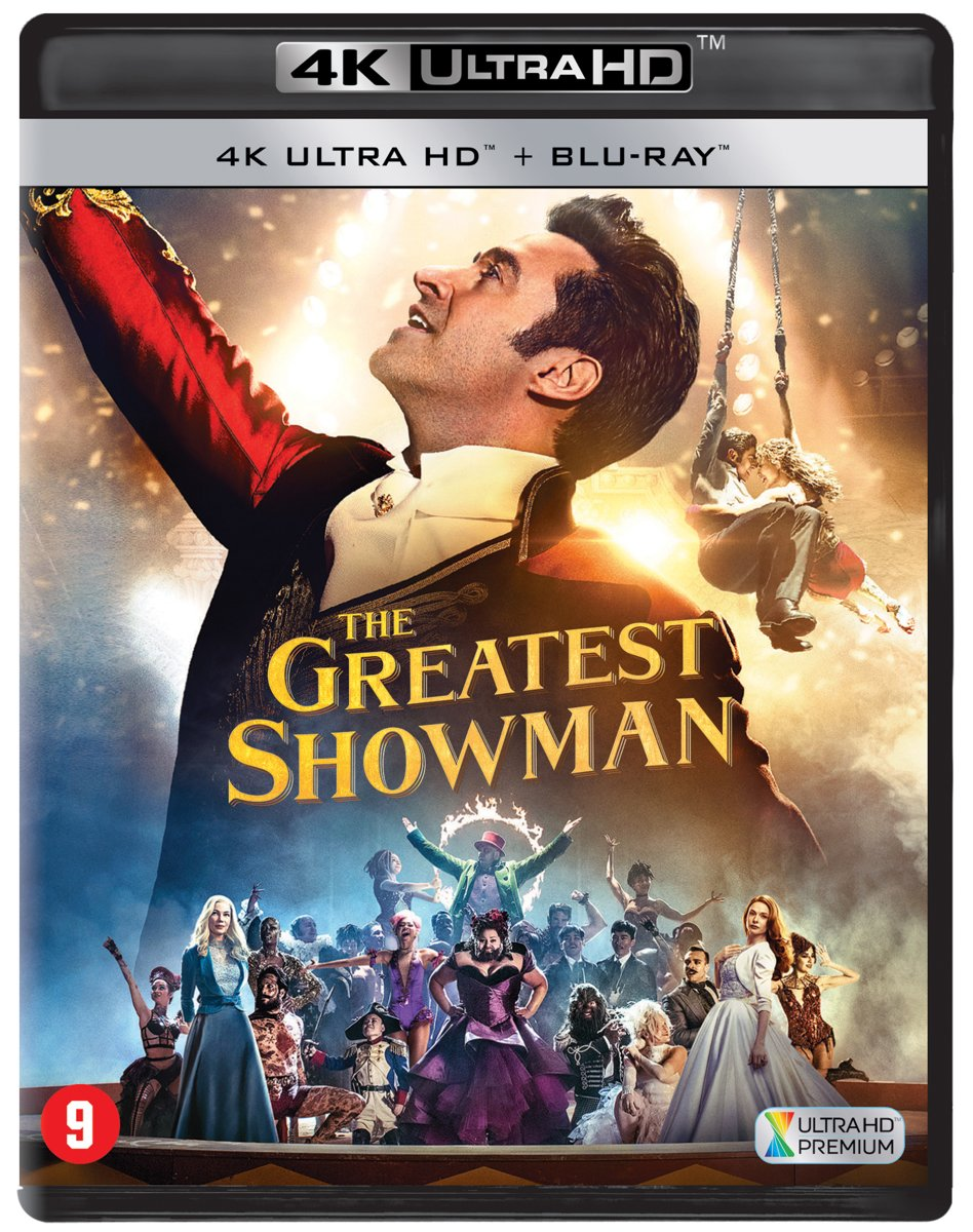 Une couverture de film pour 'The Greatest Showman'. Il y a un homme en manteau rouge et une foule de personnes.