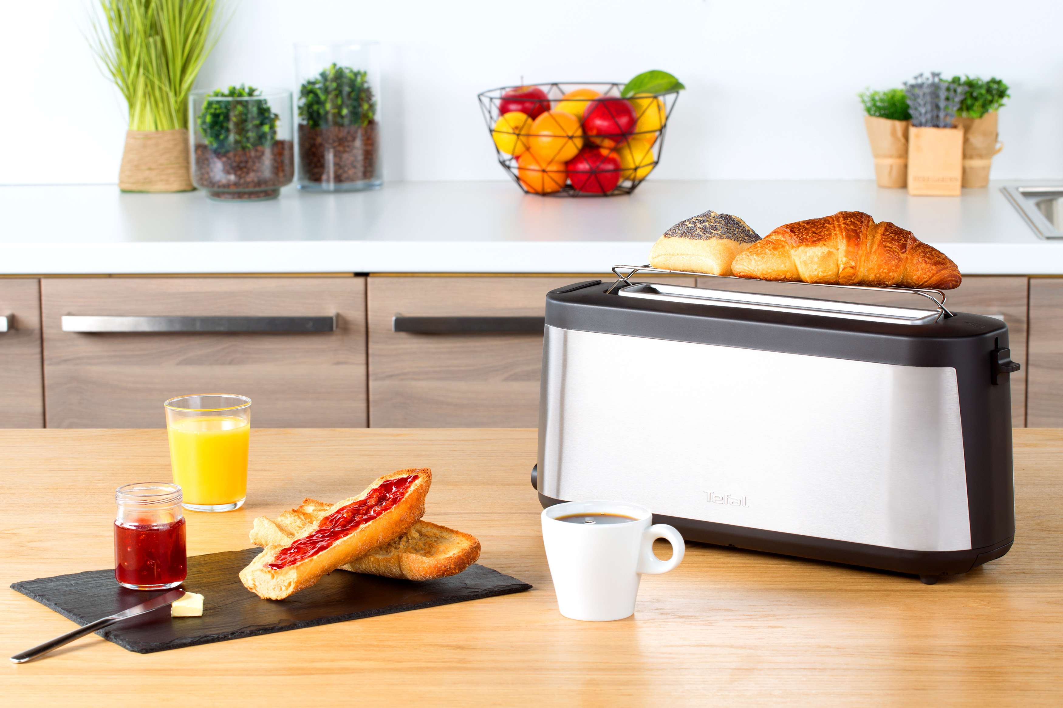 Frühstücksszene mit Toast, Croissant, Marmelade, Kaffee und Orangensaft auf Holztisch.