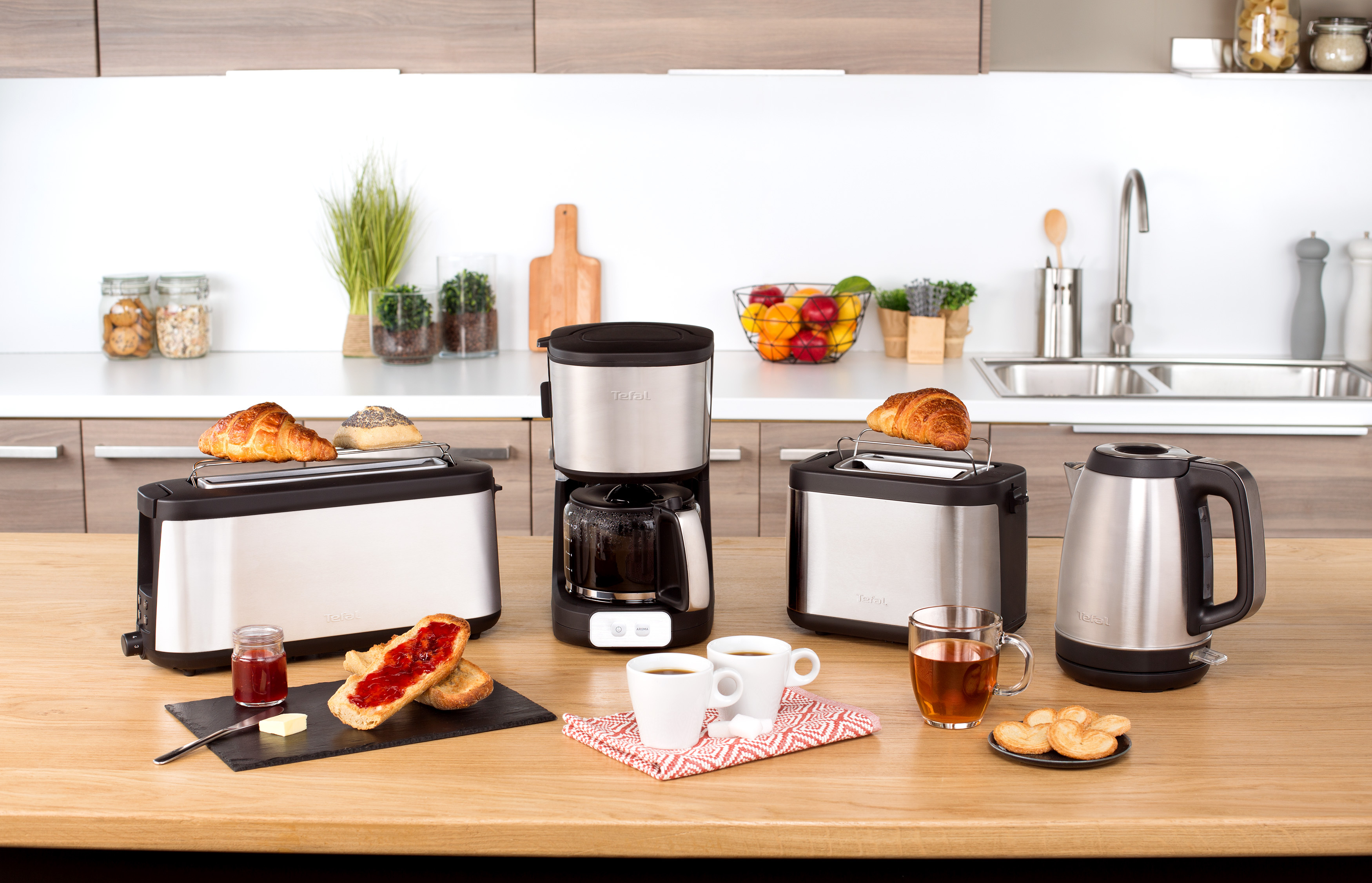 Eine Küchenzeile mit verschiedenen Geräten: Toaster, Kaffeemaschine, Wasserkocher und Speisen.
