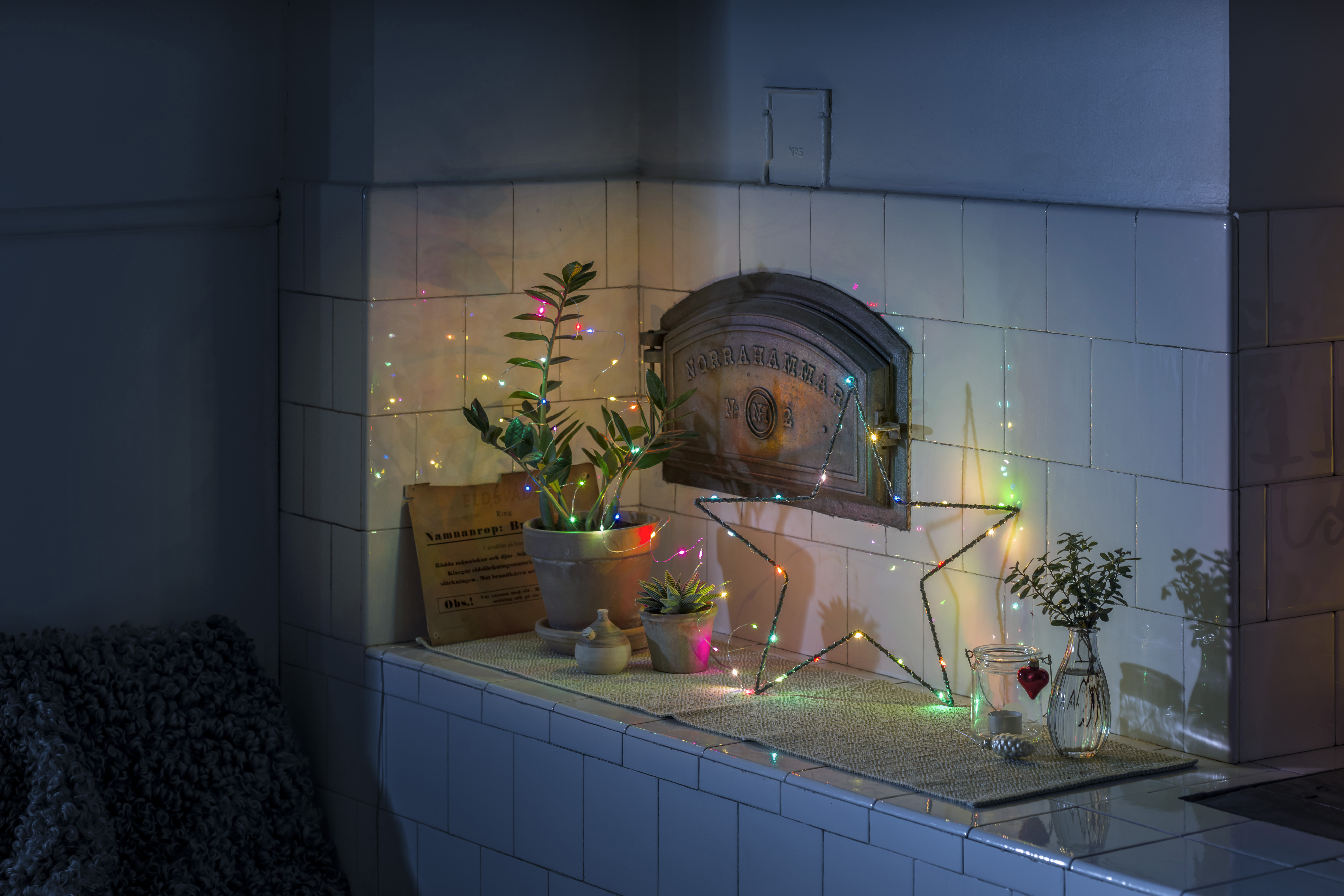 Weihnachtsbeleuchtung und Dekorationen auf weißer Oberfläche, mit dunklem Hintergrund.