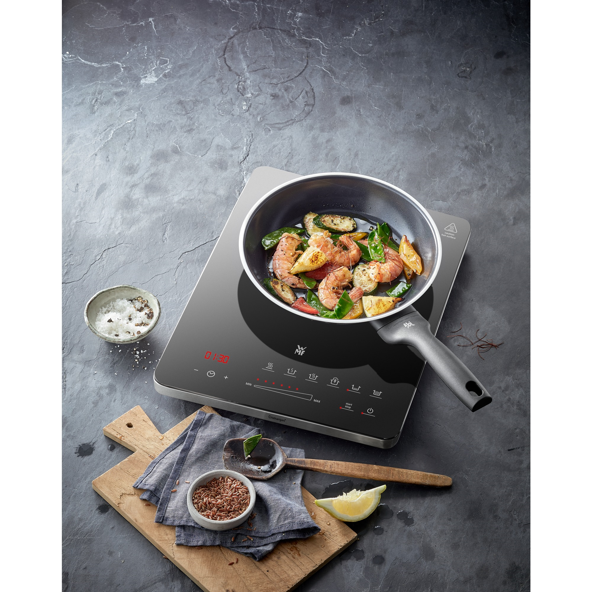 A pan with food on an induction cooktop with other cooking utensils.