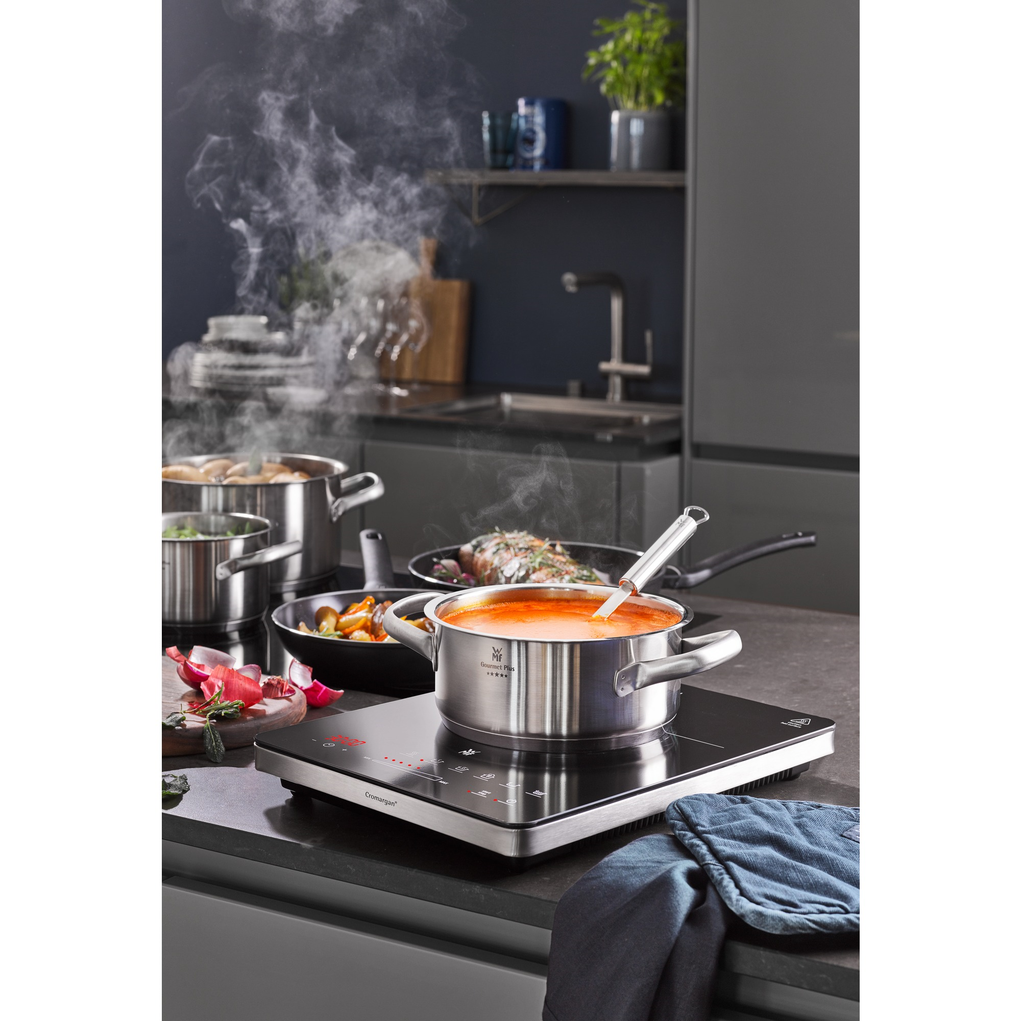 A pot of soup on an induction cooktop. Other pots and pans are visible in the background.