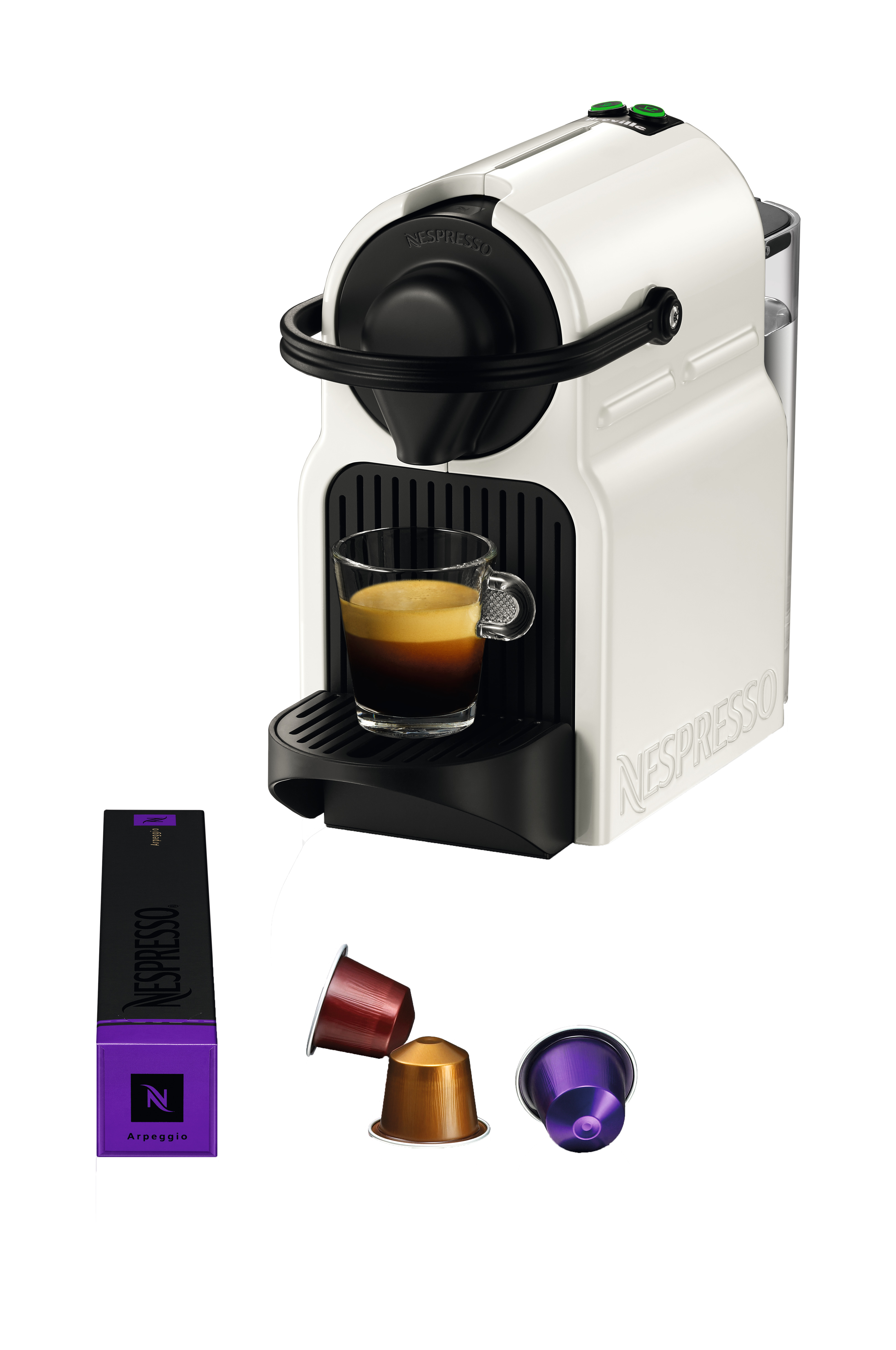 Een witte Nespresso machine met koffie in een glas, capsules en een doosje koffiecapsules.
