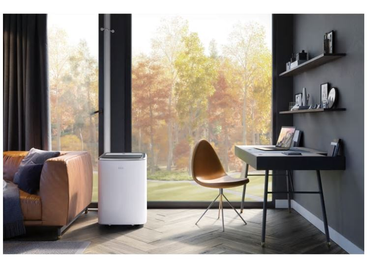 Wohnzimmer mit weißem Luftreiniger, Ledersofa und dunklem Schreibtisch am Fenster.