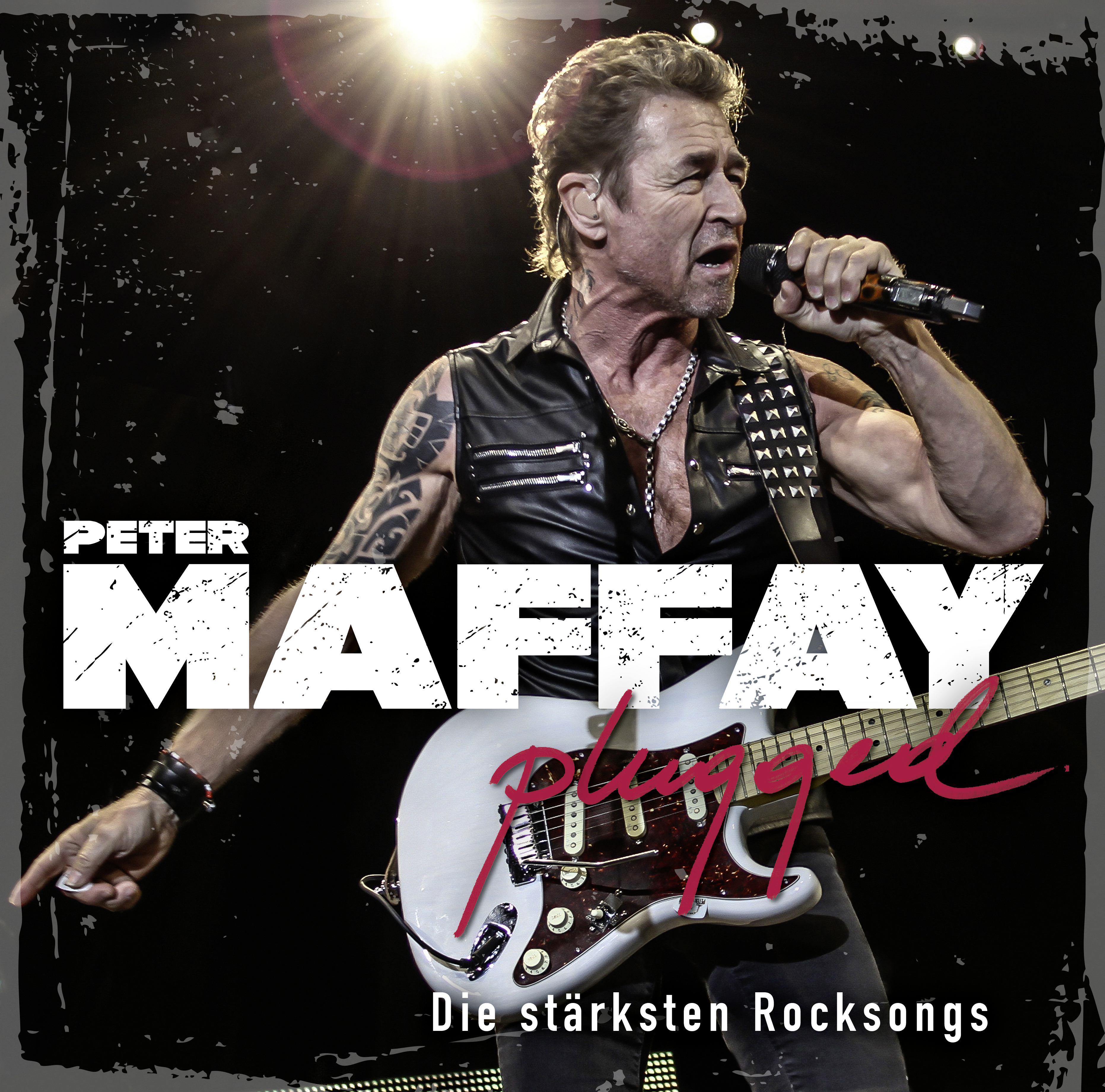 Sänger Peter Maffay auf der Bühne, mit weißer Gitarre und Wort „Plugged“ darauf.