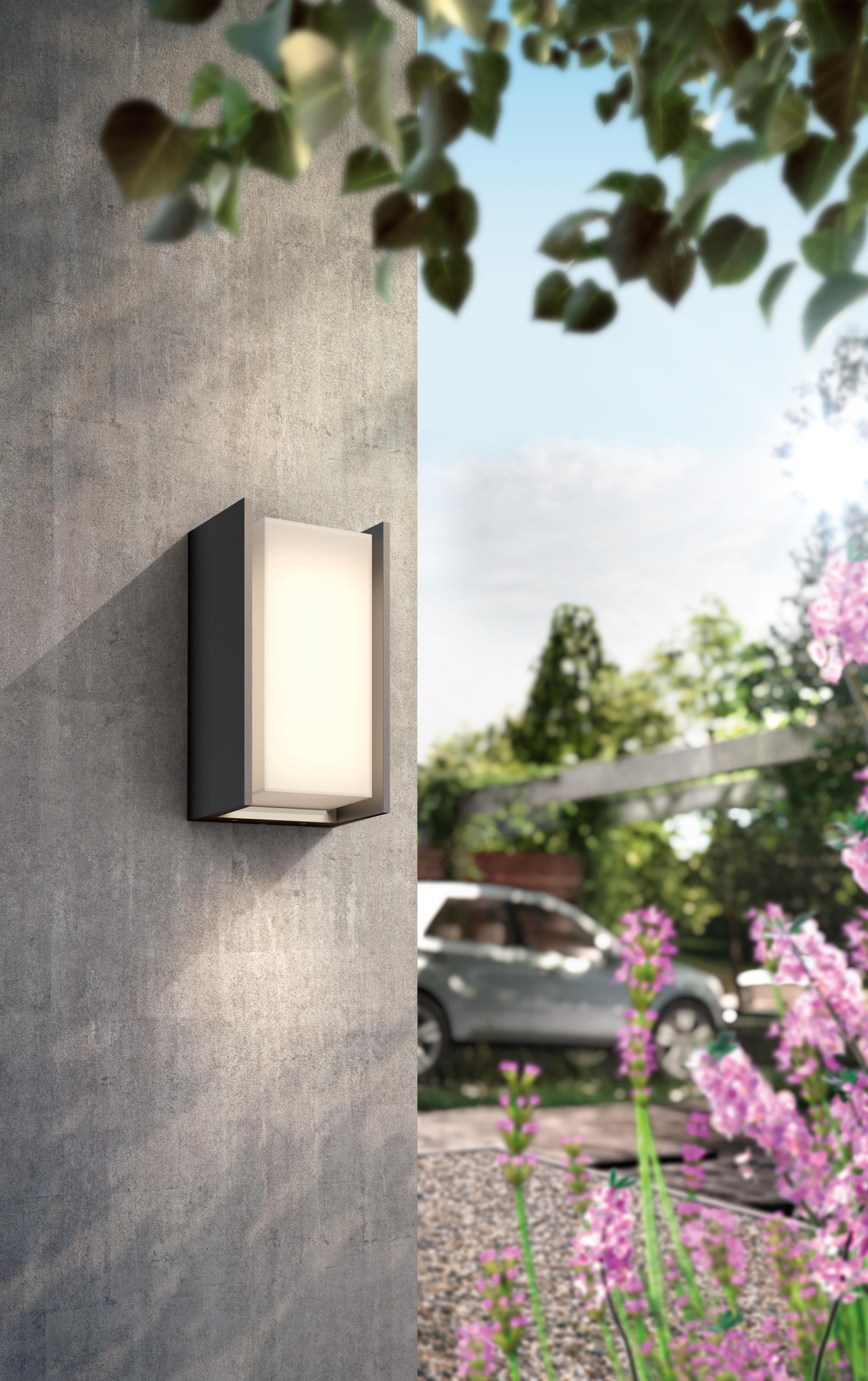 Outdoor wall light on a concrete wall. Shows a garden scene in the background.