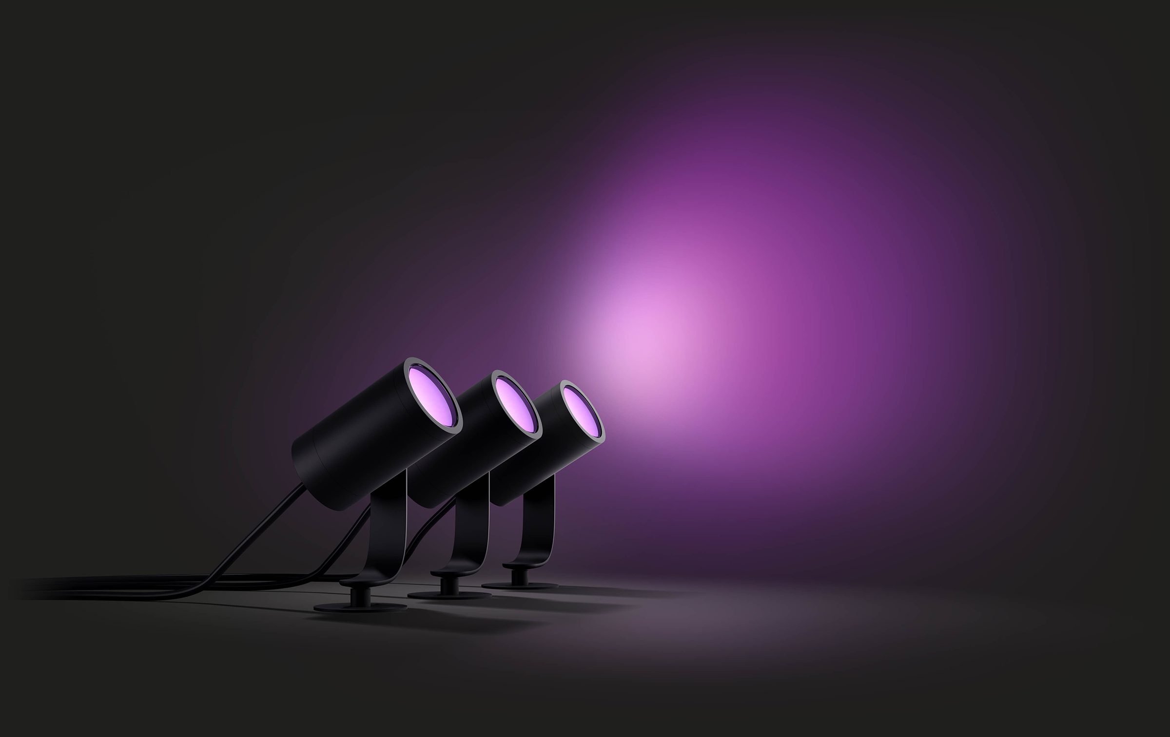 Three black spotlights illuminating a purple glow against a dark background.
