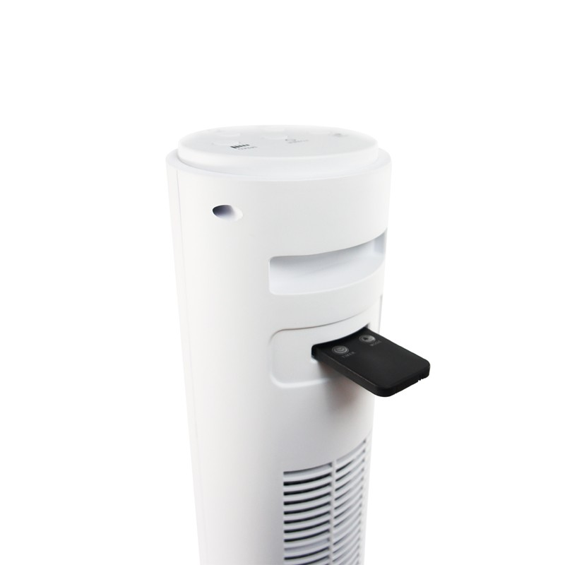 A white tower fan with a black remote control inserted. Fan has vent, control buttons, and a curved top. Isolated on white.