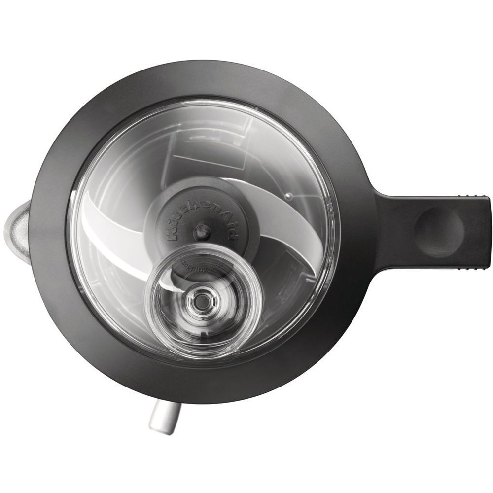 Een bovenaanzicht van een KitchenAid foodprocessor met een doorzichtig deksel en mes.