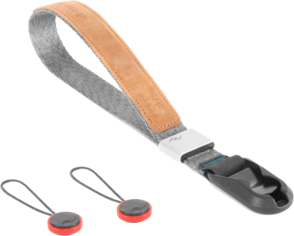 Dragonne de caméra grise et marron avec deux petites fixations rouges et noires. Logo Peak Design visible.