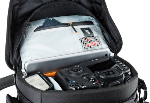 Sac photo noir ouvert. Appareil photo, tablette et autres objets à l'intérieur. Intérieur gris. Extérieur noir. Fond blanc.