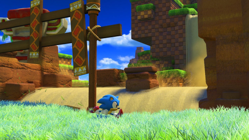 Sonic le hérisson courant dans une zone herbeuse verte près d'une structure marron.