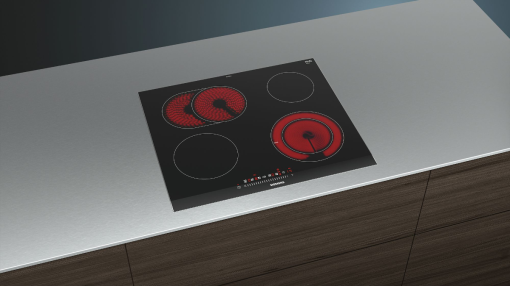 Une plaque à induction noire avec quatre zones de cuisson sur un plan de travail.