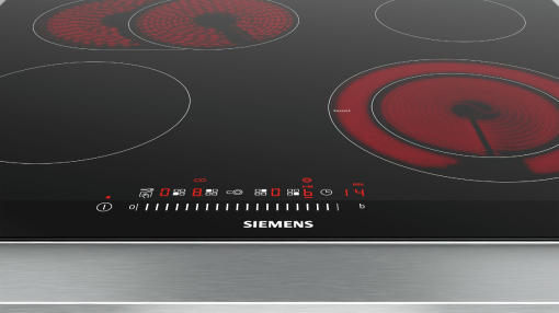 Une plaque à induction Siemens noire avec quatre zones de cuisson, dont deux rougeoient.