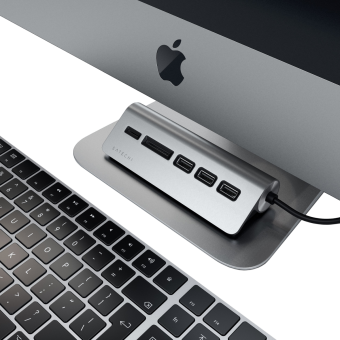 Ein silberner Satechi USB-Hub befindet sich unter einem iMac und einer Tastatur.