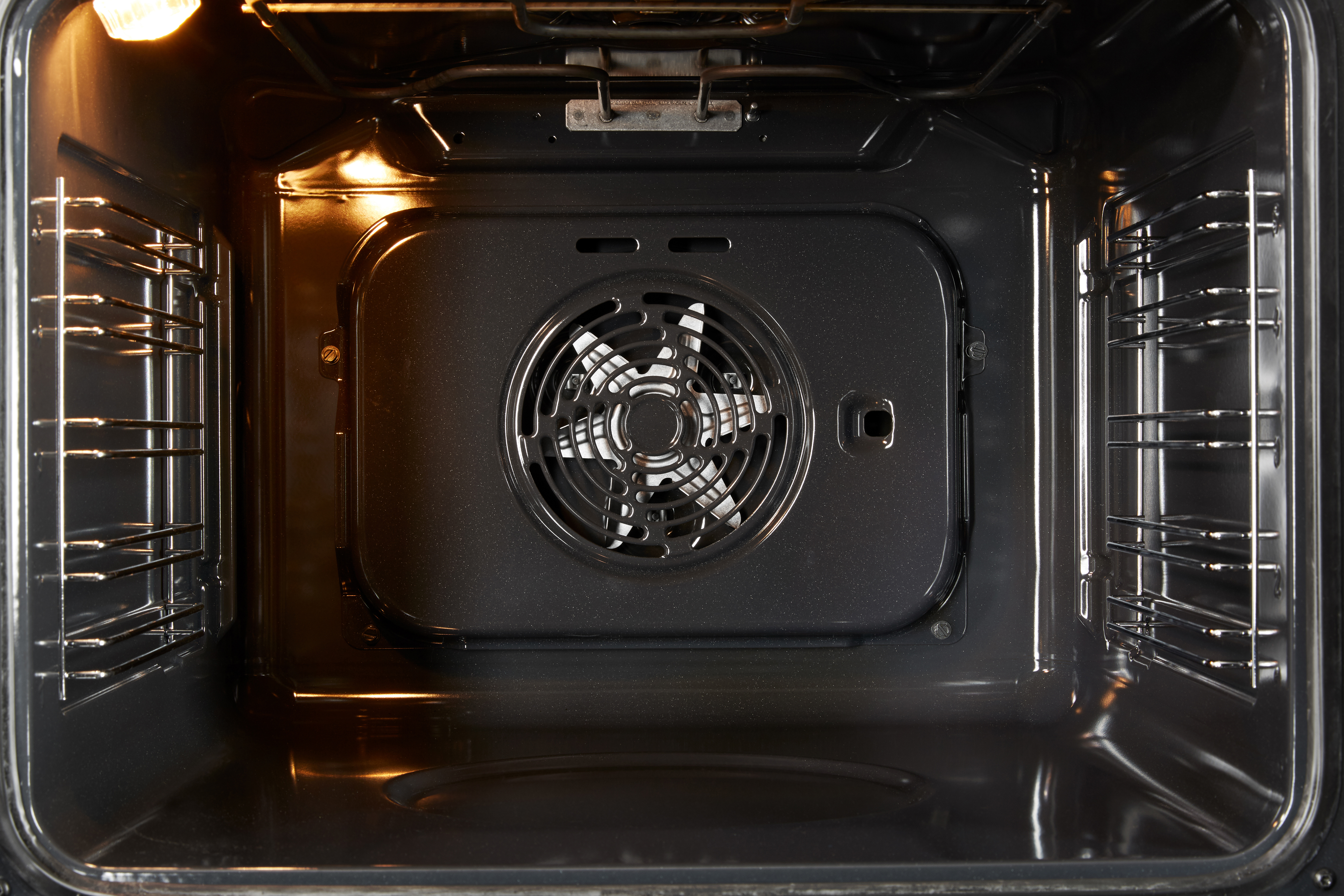 Die Innenseite eines Ofens. Er hat Roste, einen Ventilator und ein Licht. Das Innere ist dunkel.