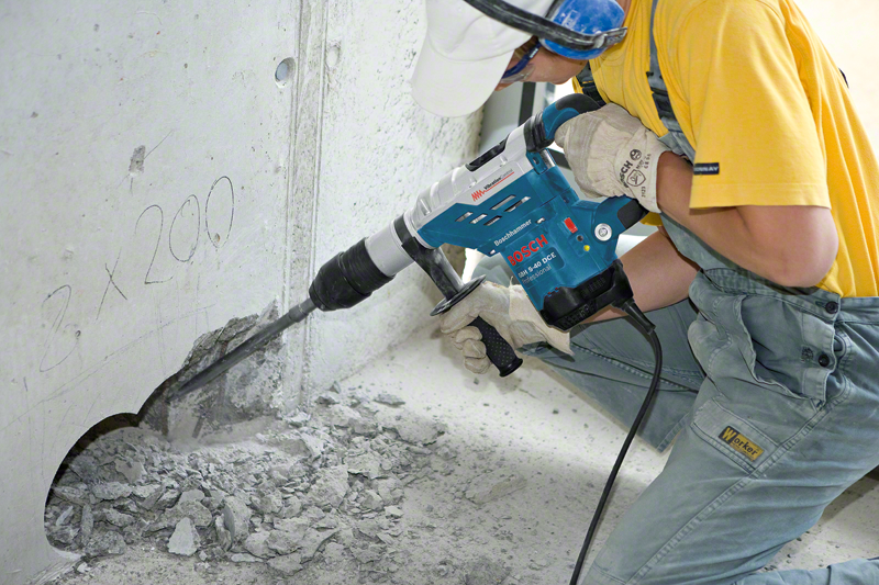Egy férfi Bosch fúrókalapáccsal fúr egy betonfalba.