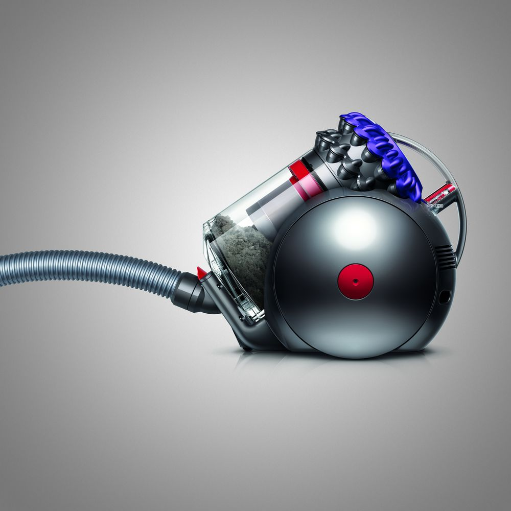 Aspirateur Dyson noir avec de la saleté à l'intérieur d'un récipient transparent.
