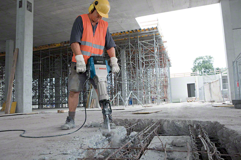 Építőmunkás bontókalapáccsal töri a betont.