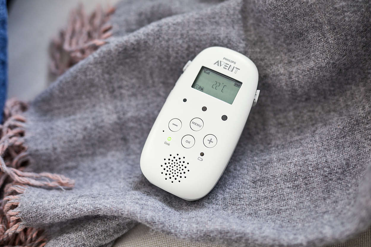 Weißer Babyphone auf grauer Decke. Knöpfe und ein Bildschirm, zeigt 22°C.