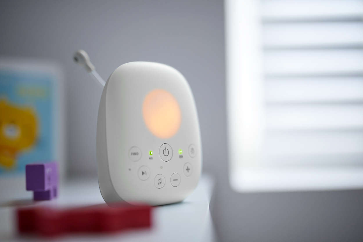 Weißer Babyphone auf einem Tisch. Oranges Licht, Knöpfe und eine kleine Antenne.