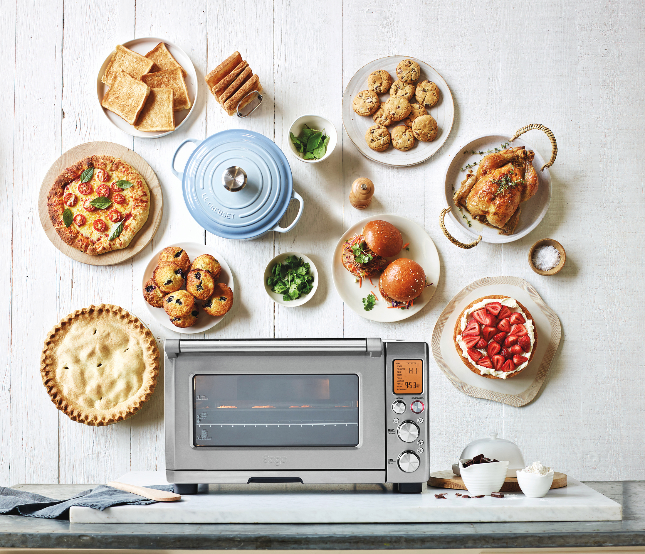 Ein Backofen mit verschiedenen Gerichten drumherum. Es gibt Teller mit Essen, darunter ein Kuchen und ein Kuchen.