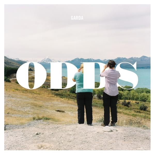 Zwei Personen betrachten Landschaft mit See, Text 'ODDS' im Bild.