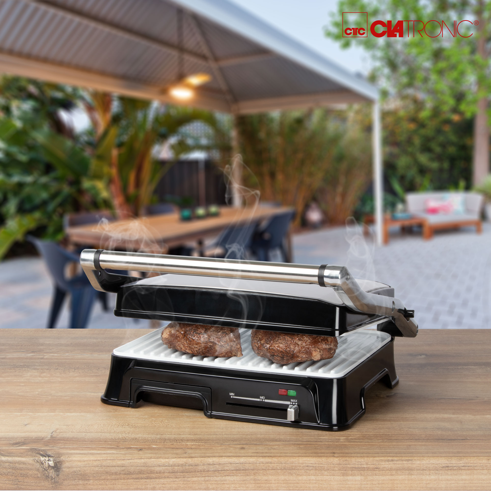 Ein Grill mit Steaks auf einem Holztisch im Freien.