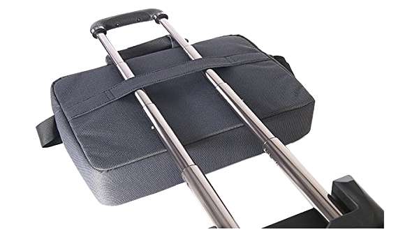 Szürke bőrönd húzófogantyúval, mögötte részben látszik egy laptop, a háttérben más táskák.