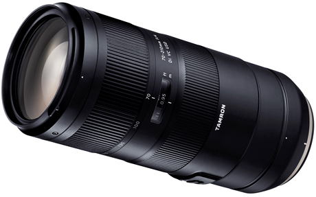 Een zwarte Tamron 70-210mm lens. De lens staat schuin met zichtbare markeringen en een focusring. De achtergrond is wit.