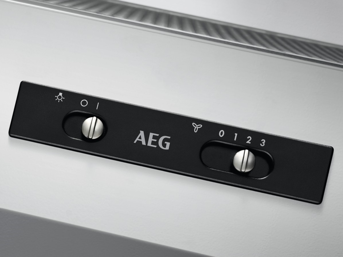 Nahaufnahme eines schwarzen AEG-Bedienfelds mit silbernen Knöpfen und weißem Text, weißer Hintergrund.