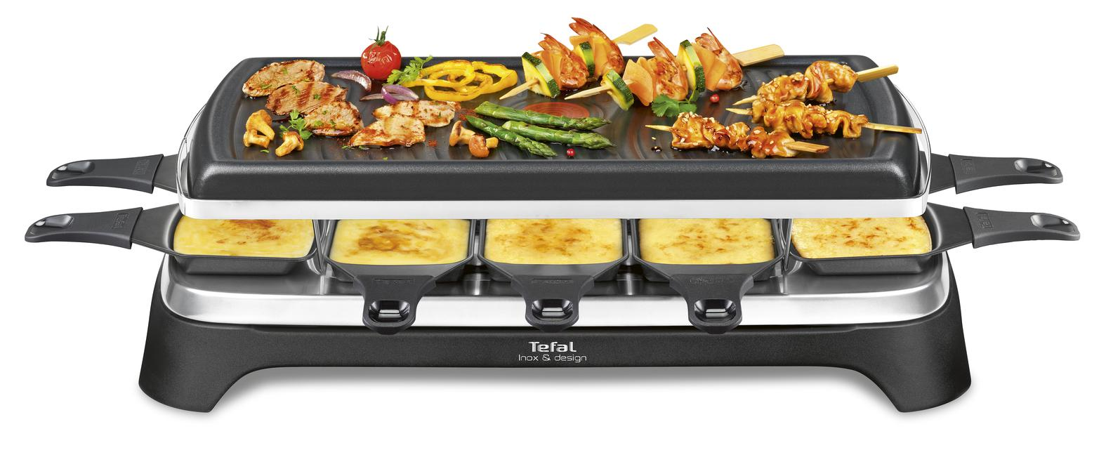 Een raclette grill met eten erop en kaas in de onderste pannen. Zwart en zilverkleurig.